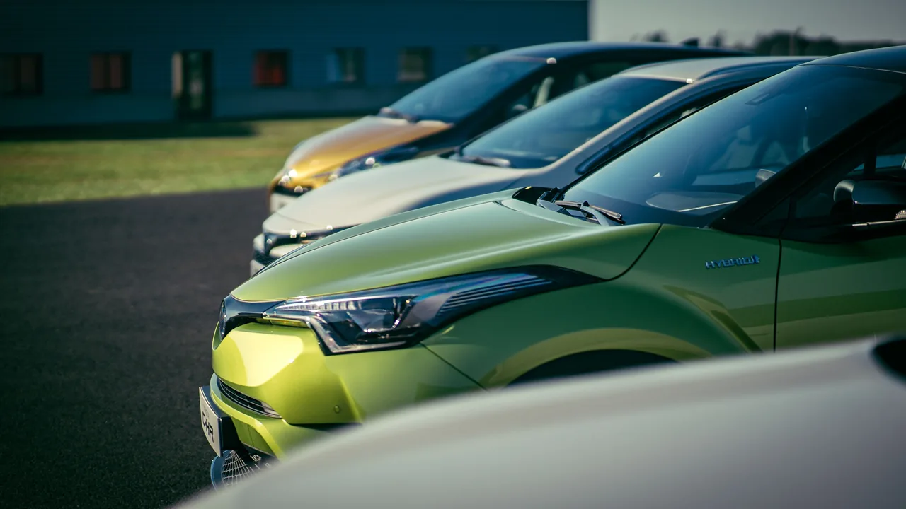 Row of cars parked outdoors, with a green car in the foreground